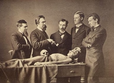 Old photo of anatomists around a cadaver. One is smoking.